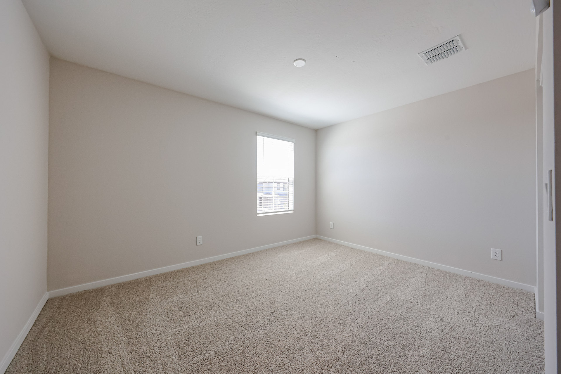 A room with a carpet and a window.