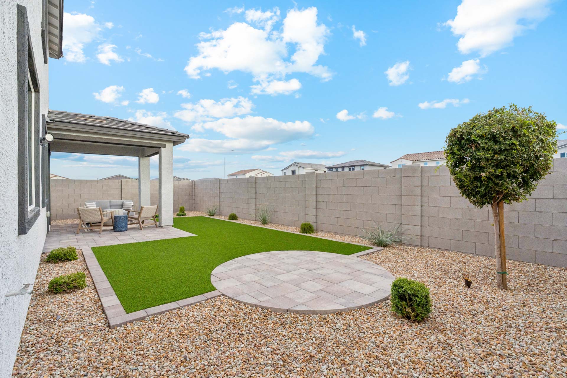 A courtyard with a tree and a building in the background.