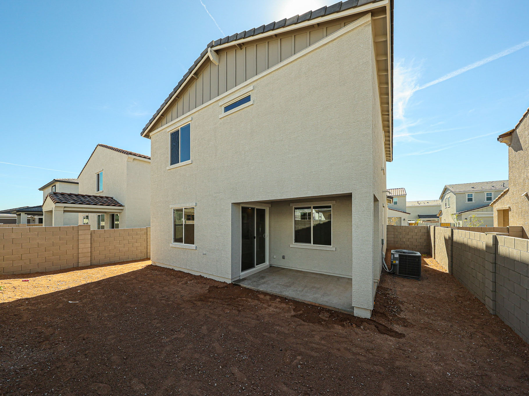 A white building with a dirt yard.