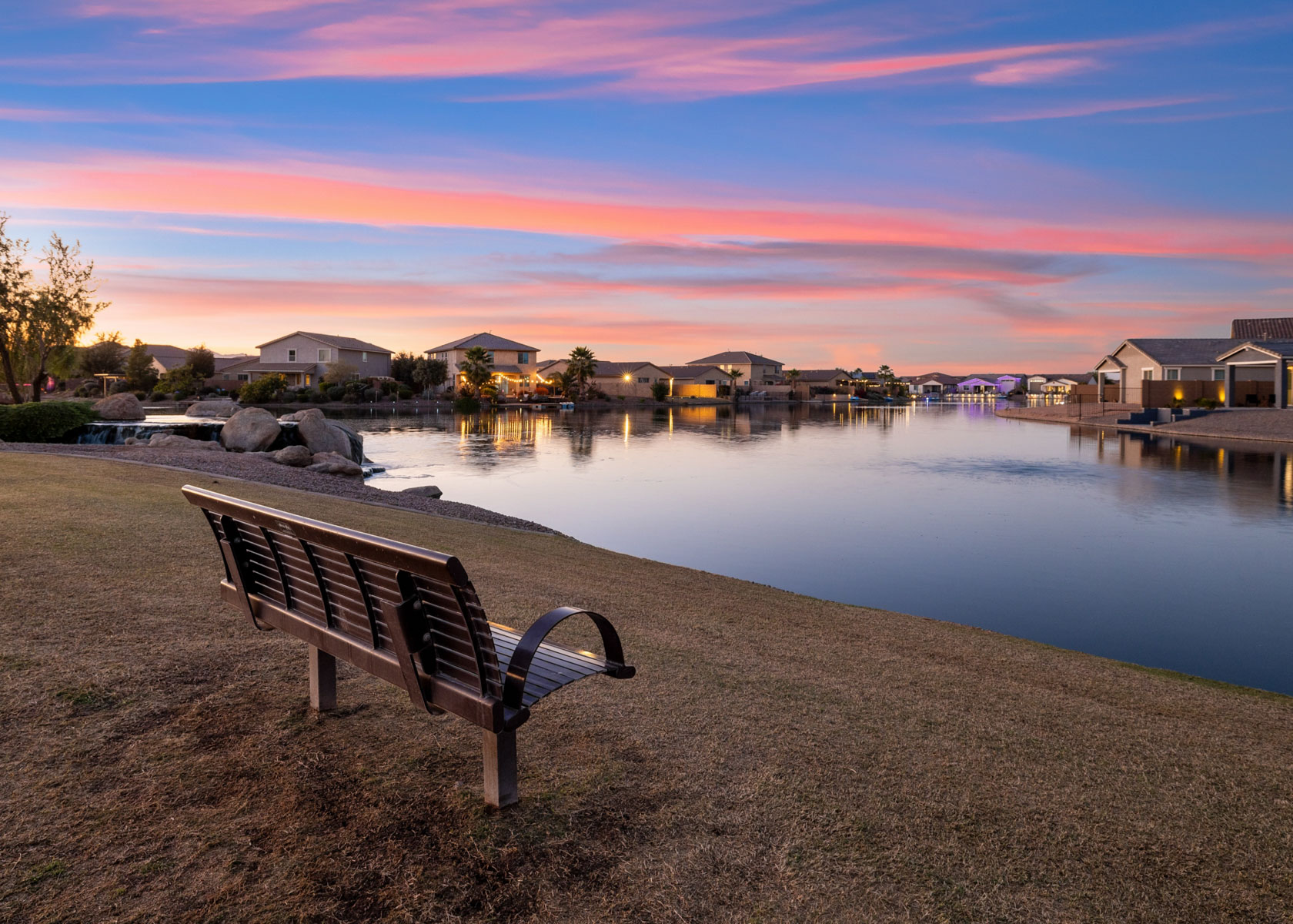 A bench sits by a body of water.