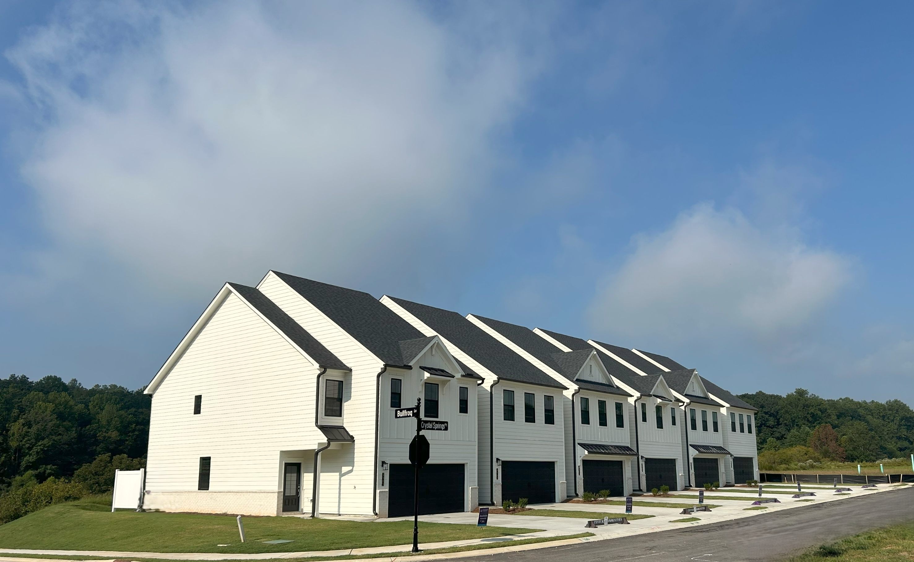 A white building with a road and trees in the background.