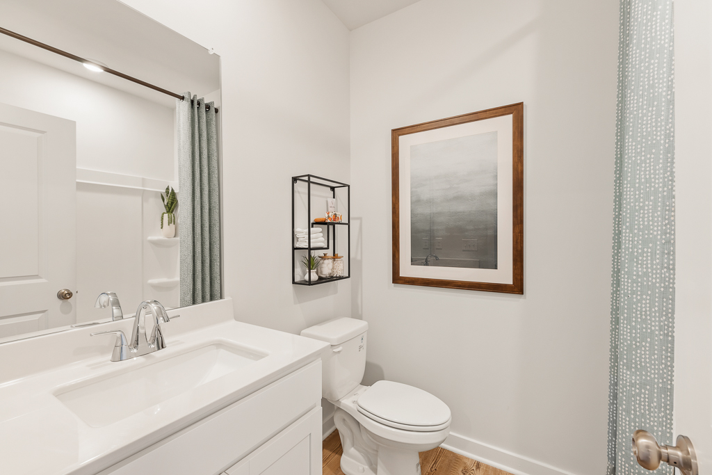 A bathroom with a sink toilet and a mirror.