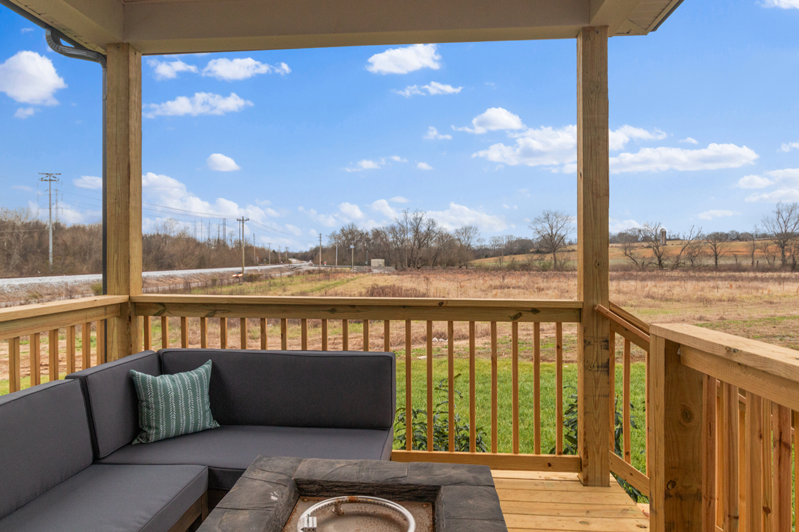 A deck with a view of a field and trees.
