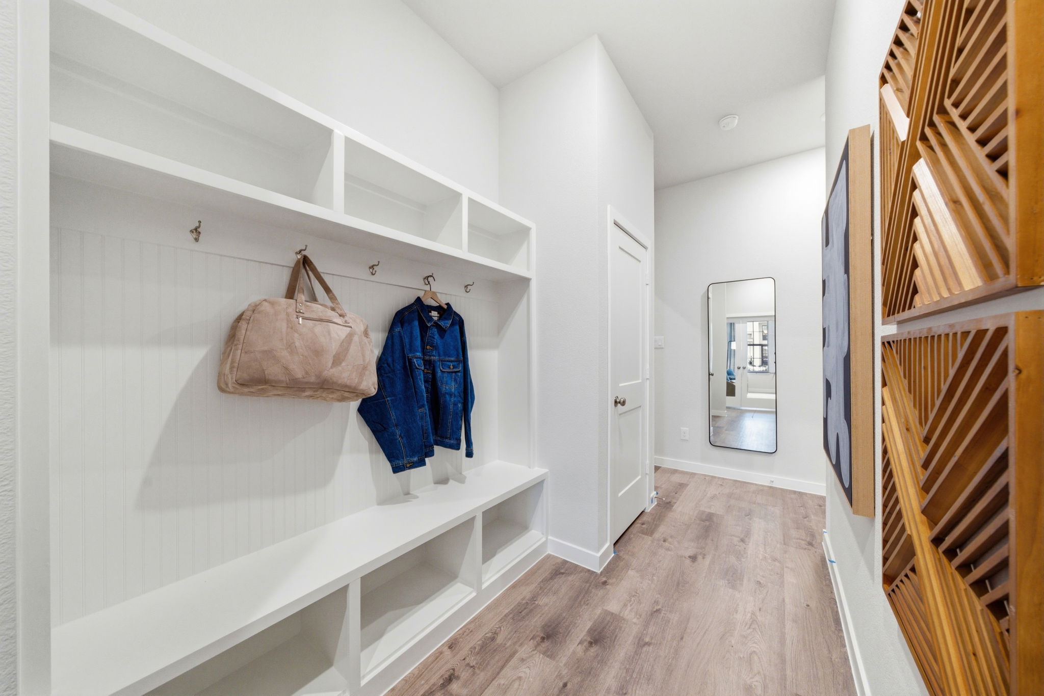 A white room with a wood floor and a wood staircase.
