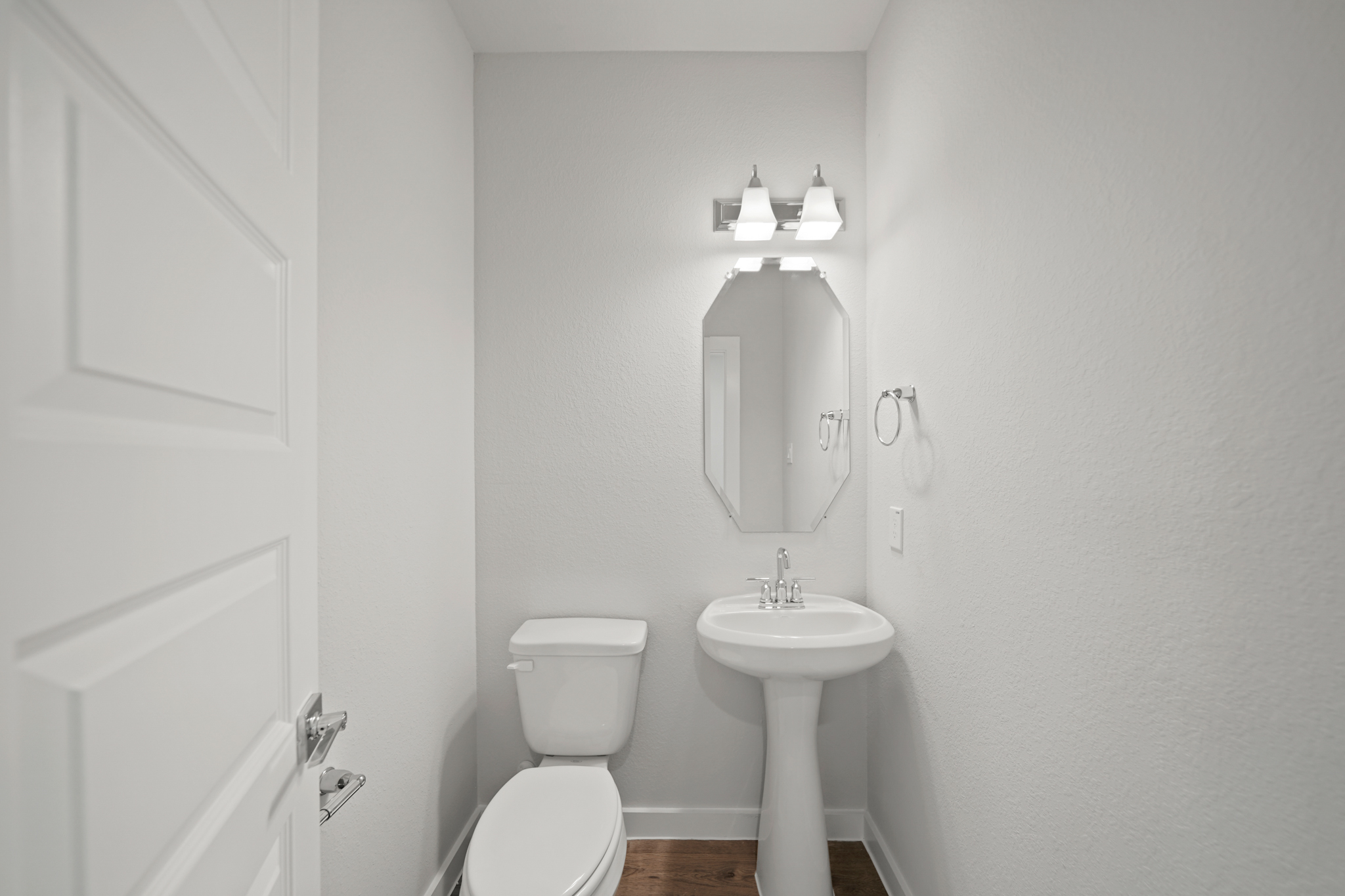 A bathroom with a sink toilet and mirror.