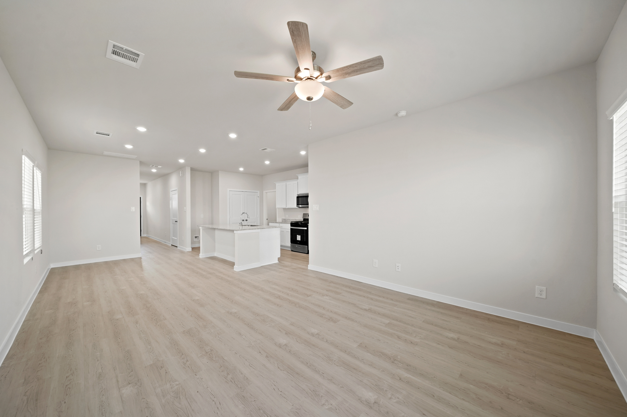 A large empty room with a ceiling fan and a wood floor.