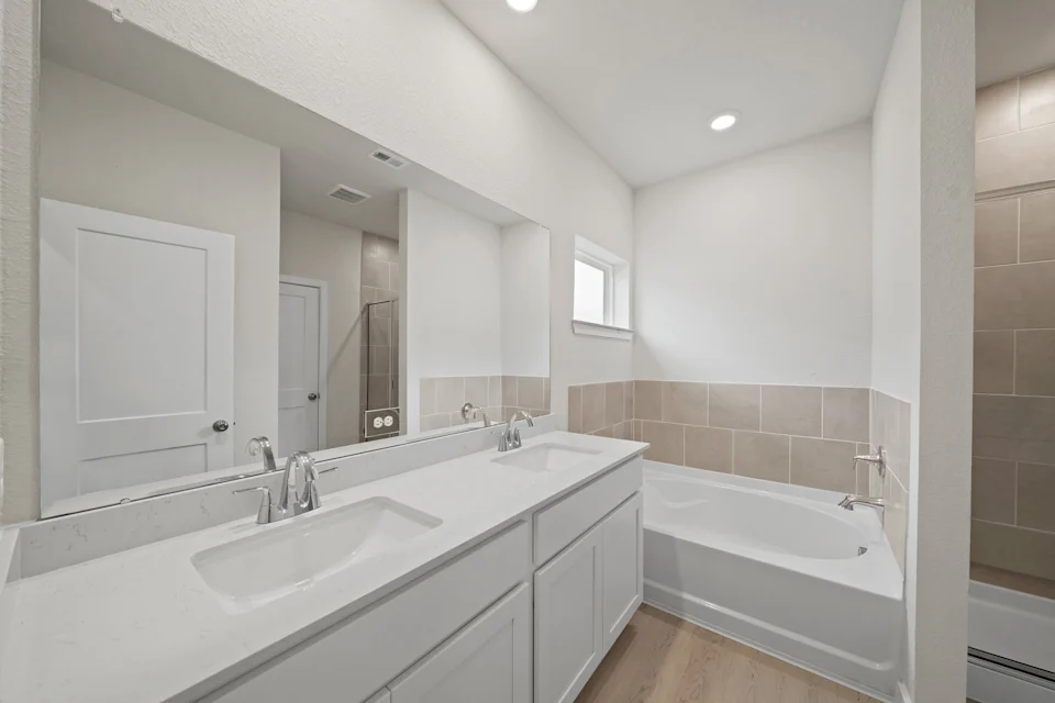 A bathroom with a tub sink and a mirror.