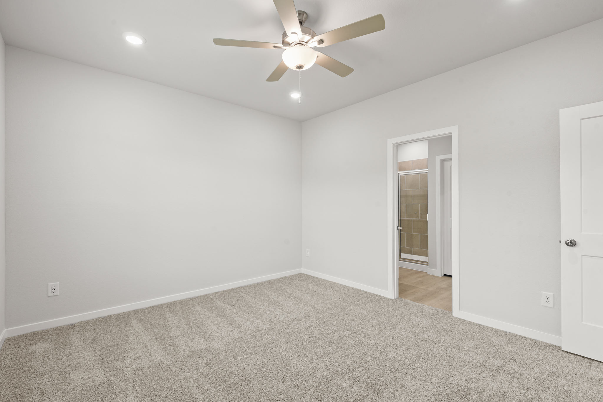 A room with a ceiling fan and a door.