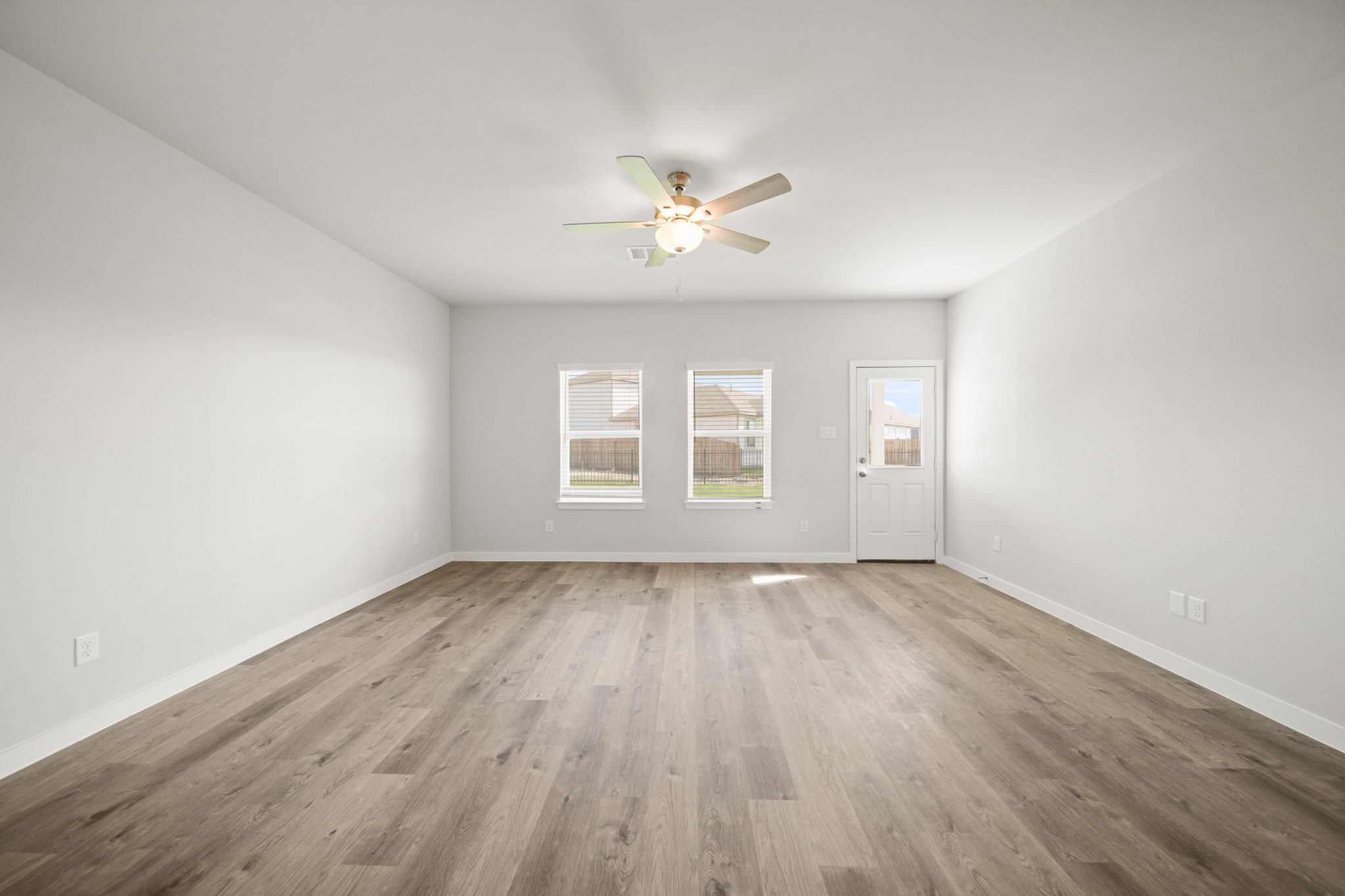 A room with a ceiling fan and a wood floor.
