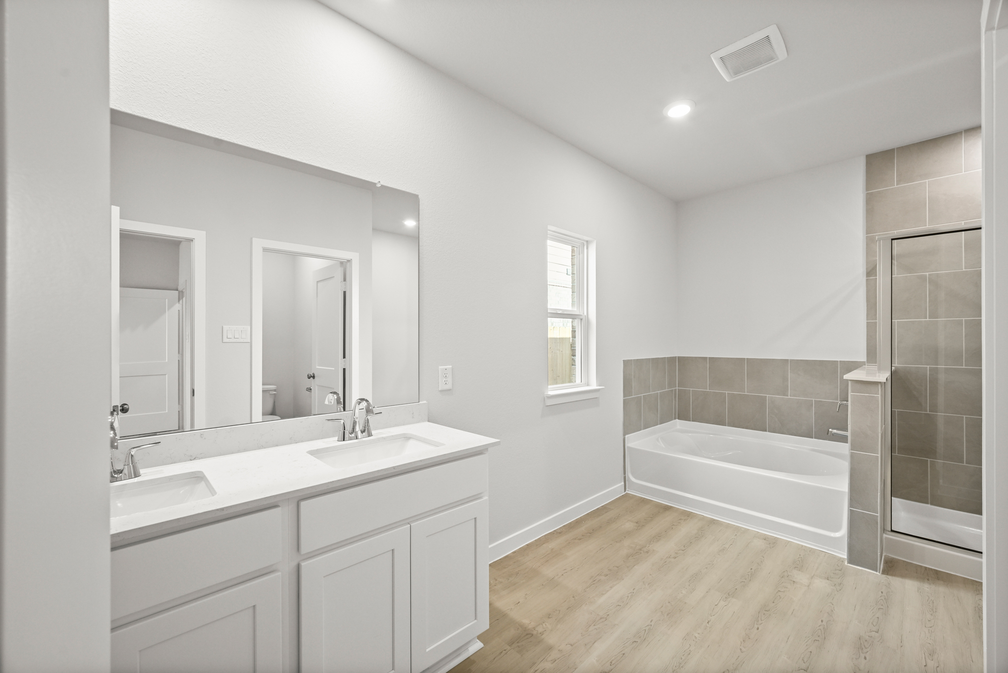 A bathroom with a tub sink and mirror.
