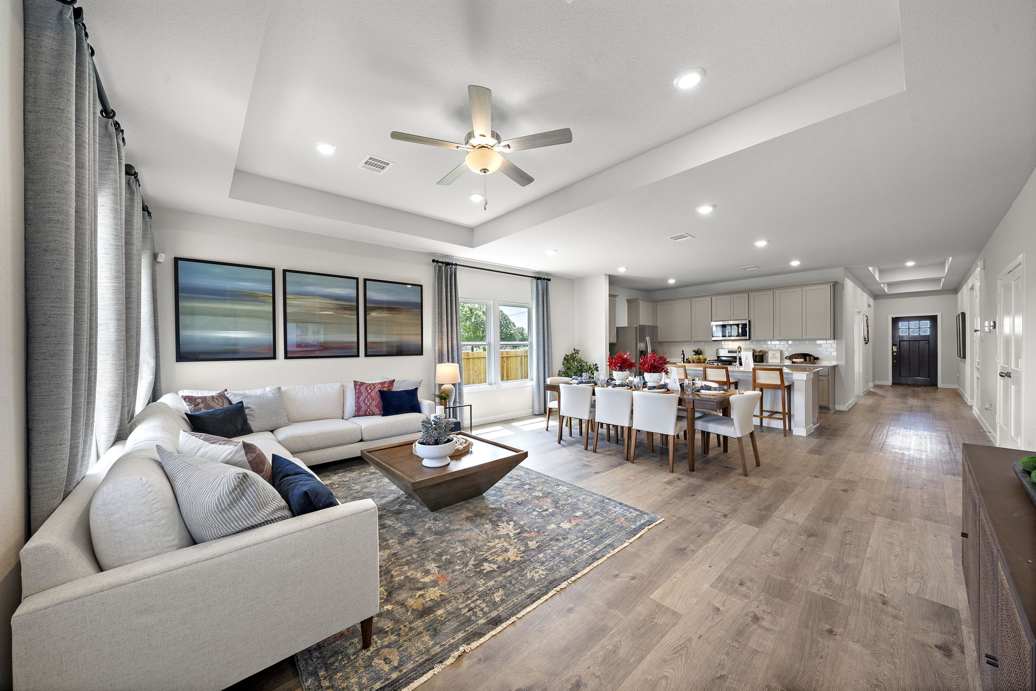 A living room with a large ceiling fan and a large dining room.