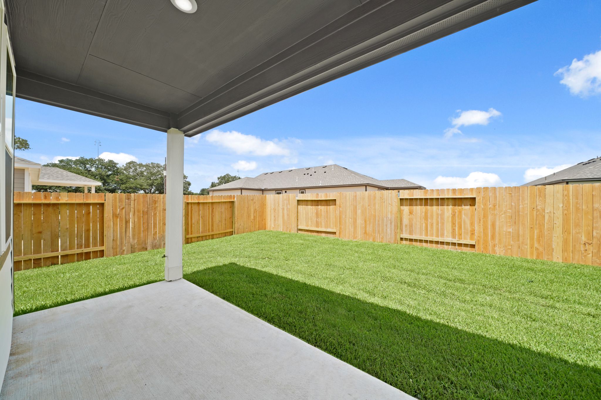 A fenced in yard with a walkway and grass and a building.