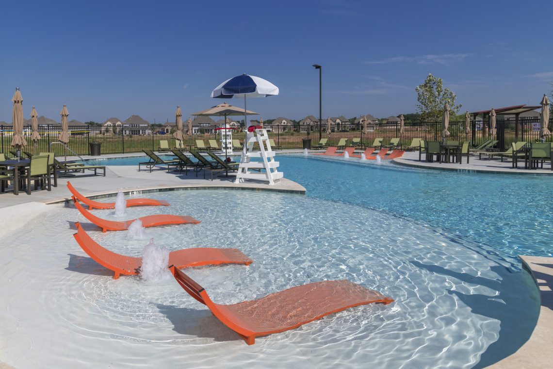 A pool with orange chairs and a slide in it.