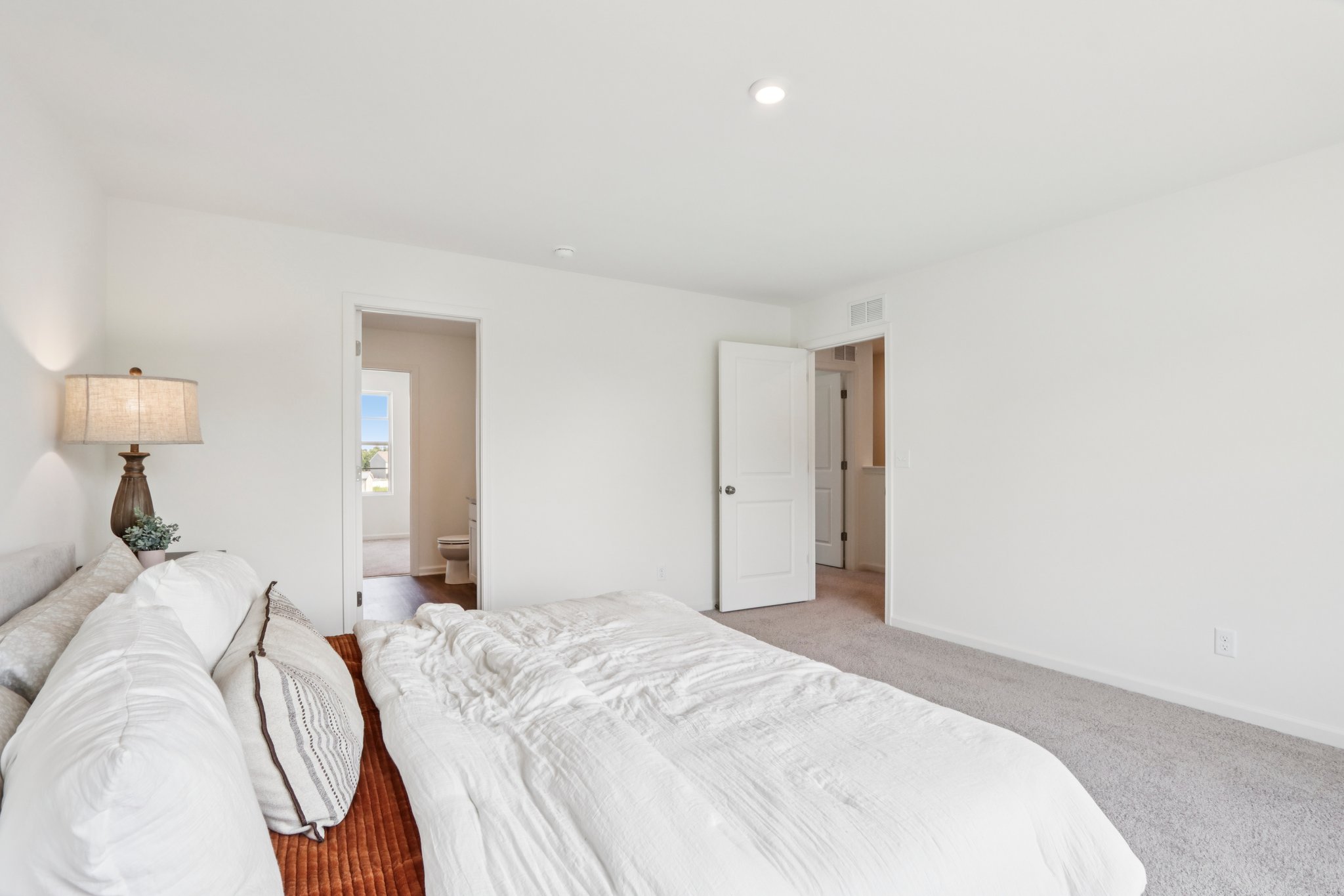 A bedroom with a bed and a lamp.